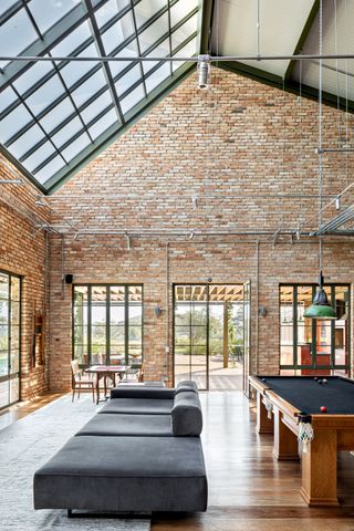 A living room in brick, with a long minimalist couch in the centre