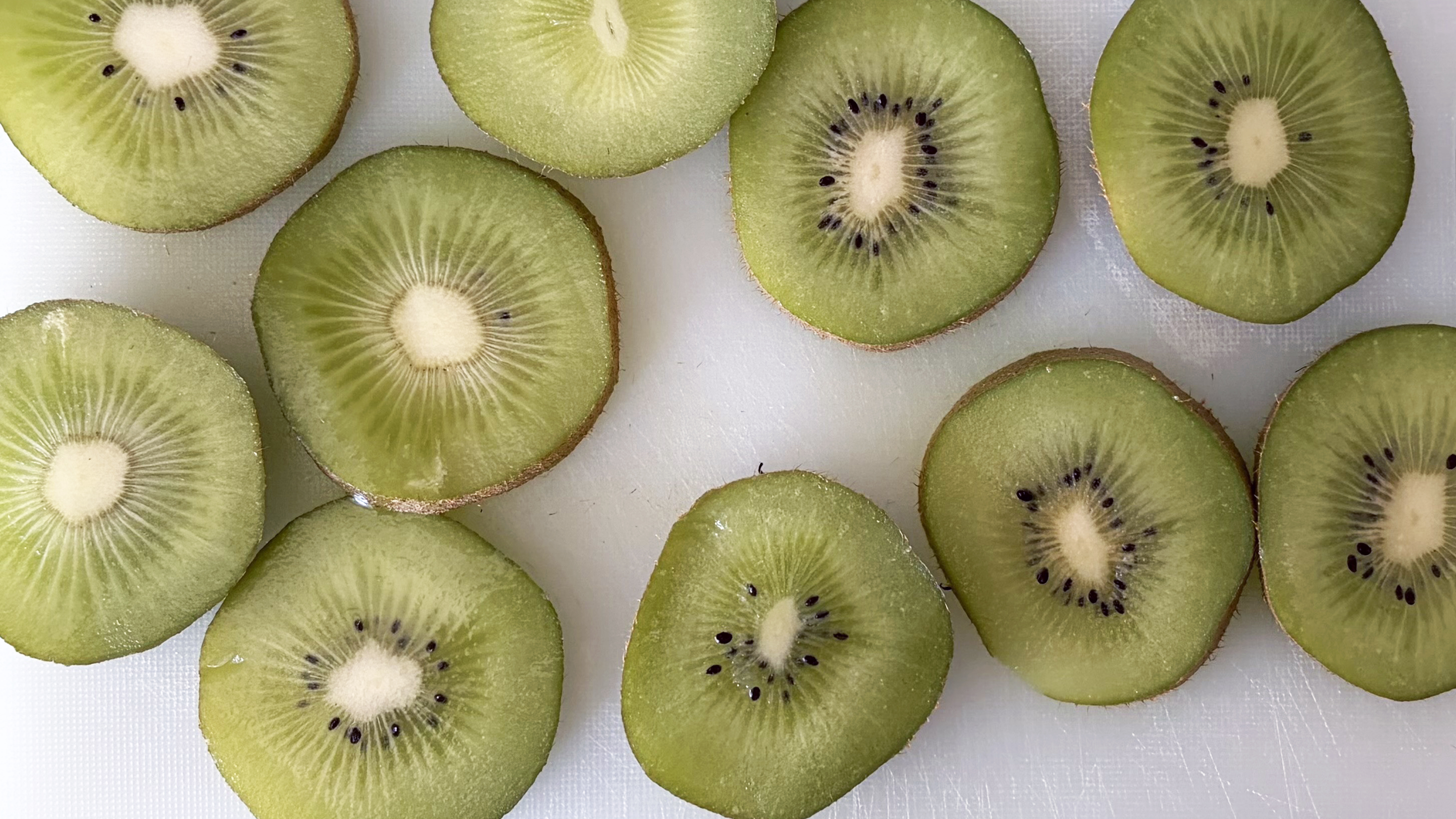 A close up of a sliced kiwi on a chopping board