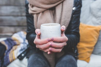 Woman&#039;s hands holding a round white mug