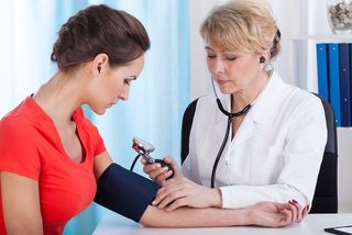 A woman has her blood pressure checked by a doctor.