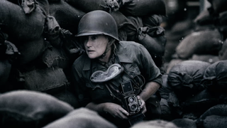 A helmeted Lee Miller (Kate Winslet) shelters amongst piles of sacks in Lee