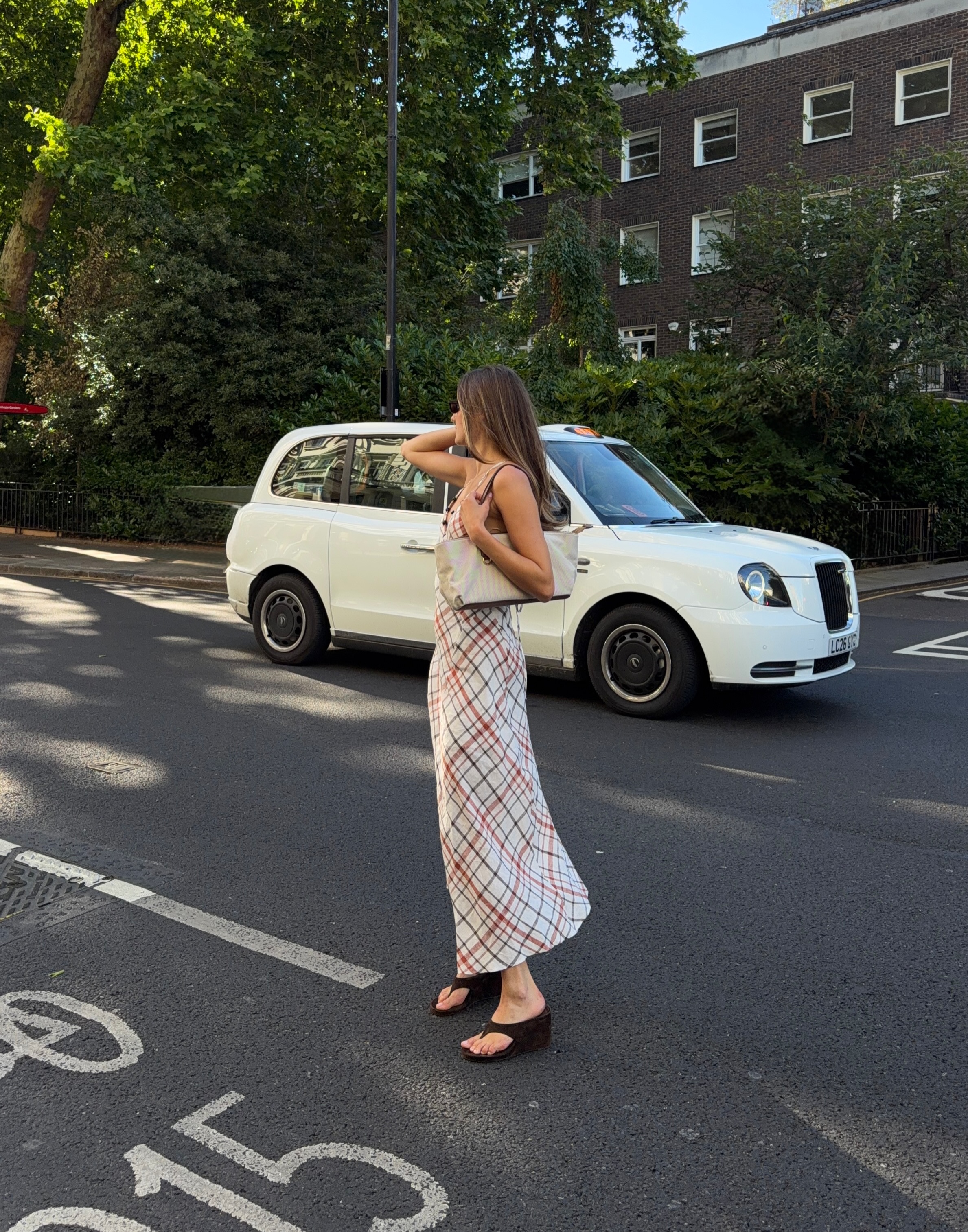 Influencer Sara Walker wearing a check slip dress, velvet wedge sandals and canvas bag.
