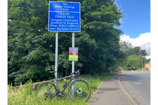 The Liv Langma Advanced Pro 0 leaning up against a road sign that reads Cragg Vale