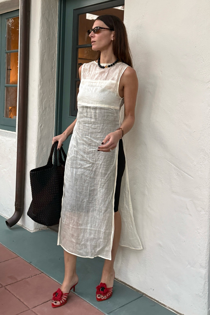 a woman wearing a white dress, beaded necklace, and red heeled sandals