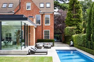 A red brick house with a glass extension and a swimming pool