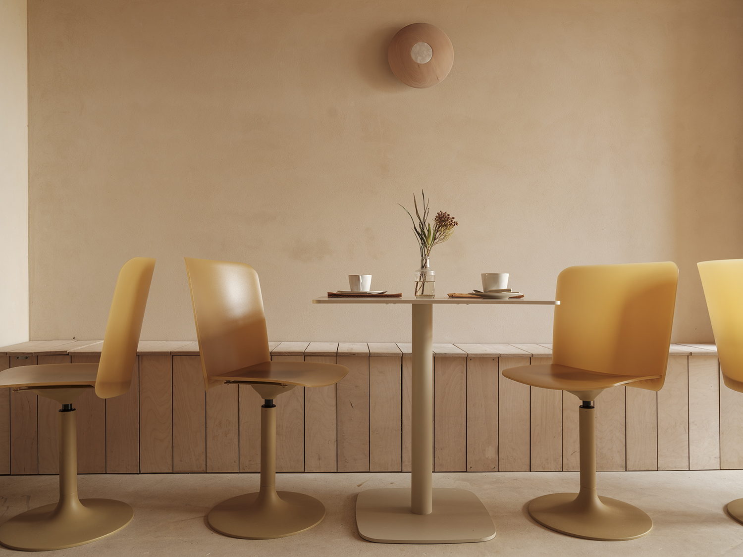 A light brown-shaded cafe features plaster and wood furnishings boasting a minimalist style.