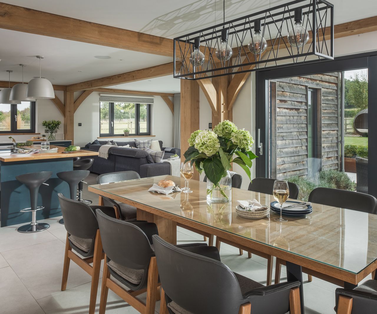 A large dining table with statement ceiling lights in an open plan kitchen area