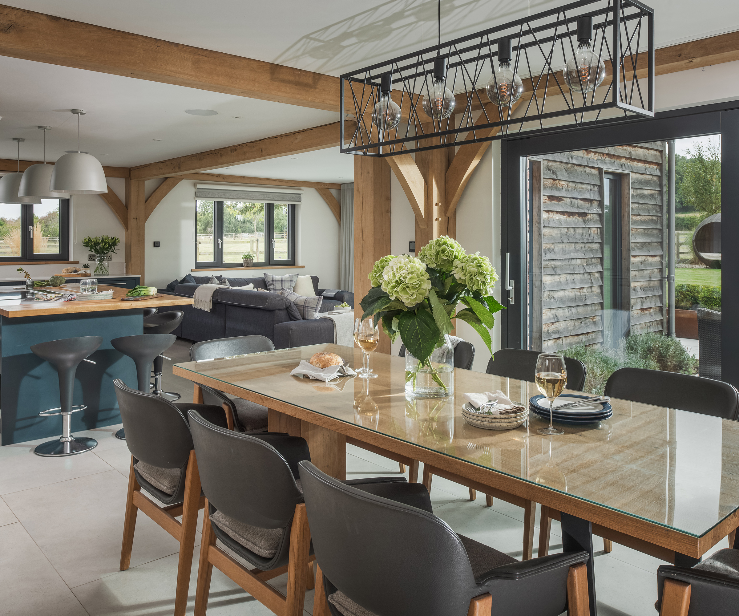 A large dining table with statement ceiling lights in an open plan kitchen area