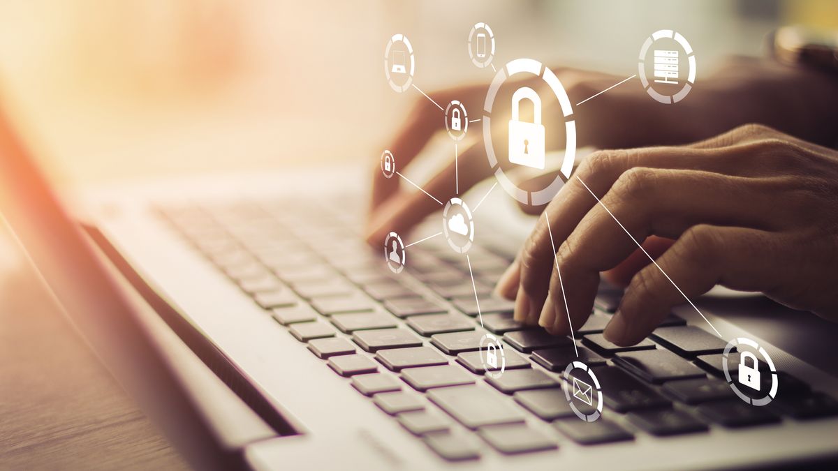 Hands typing on a laptop with padlock and network graphic superimposed