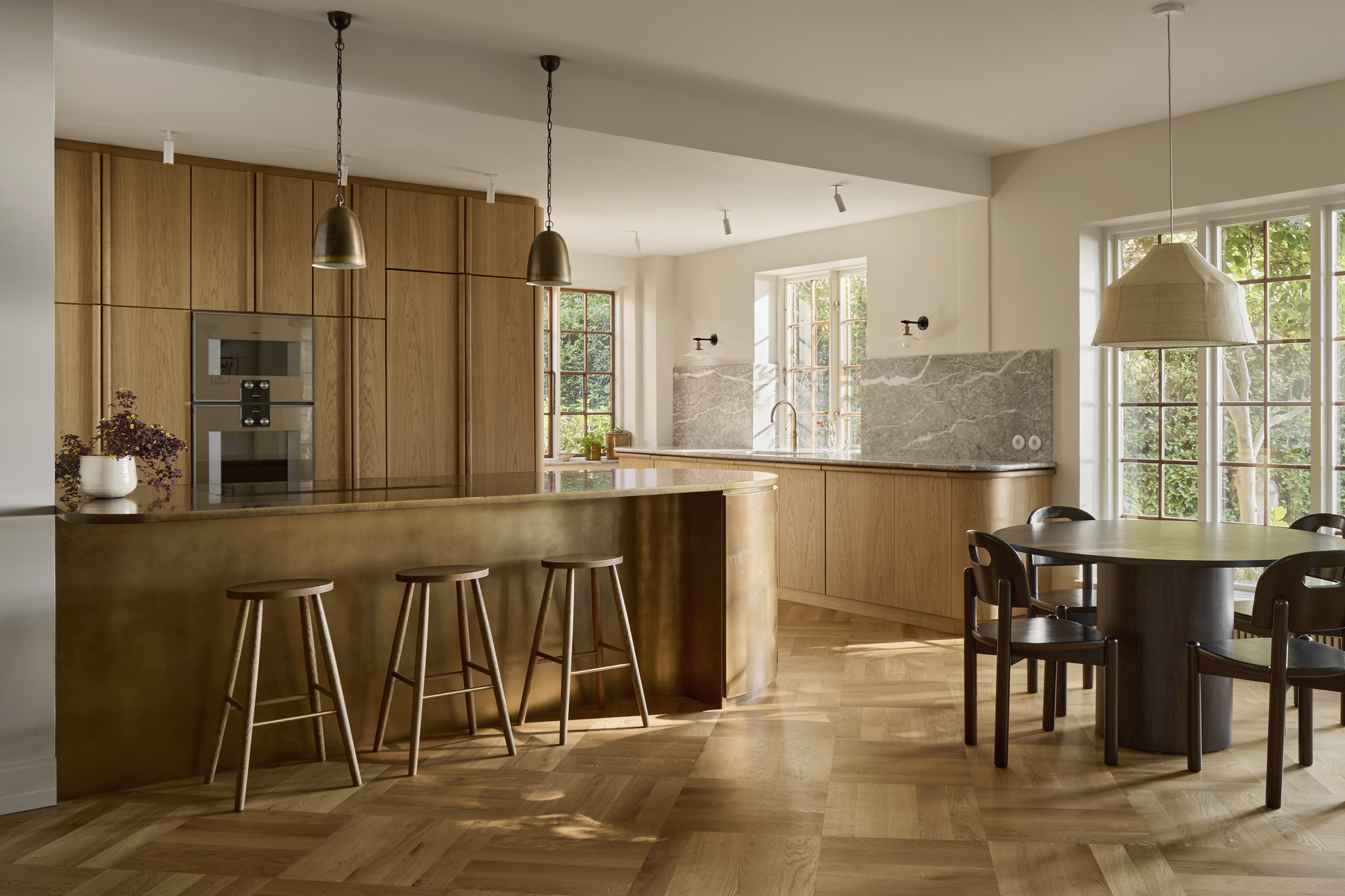 A Scandi kitchen with parquet wooden flooring, a bronze kitchen island, and natural wooden cabinetry