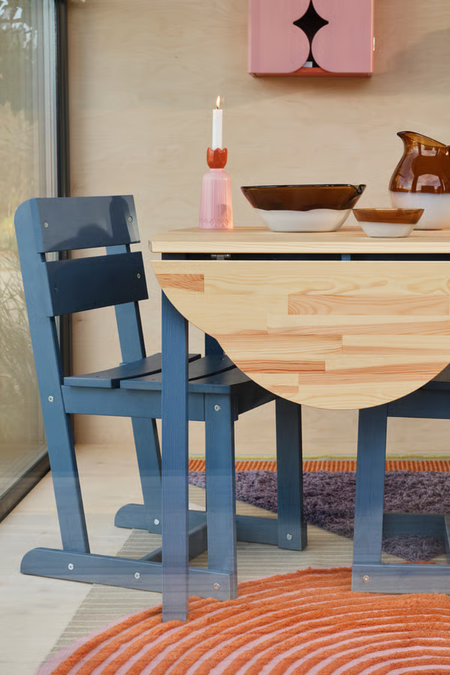Breakfast table vignette featuring a wooden folded-leaf tabletop, blue chairs, and eclectic table decor 