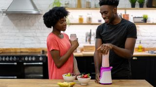 A man and woman making a protein smoothie together