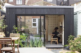 home office in bespoke garden room with black cladding at end of garden