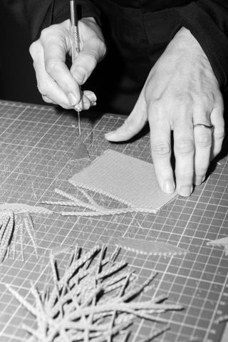 Eva Jospin's hand seen cutting cardboard