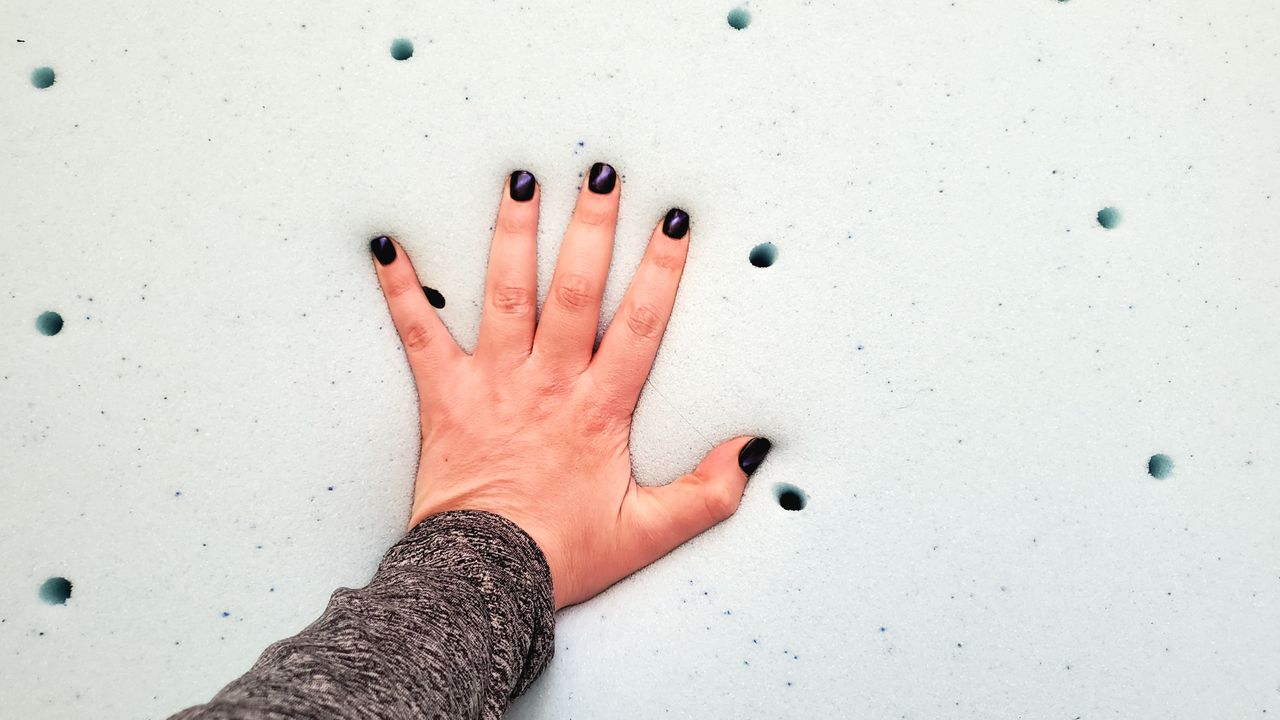 A manicured hand feels the light blue surface of the Lucid Gel Memory Foam Mattress topper