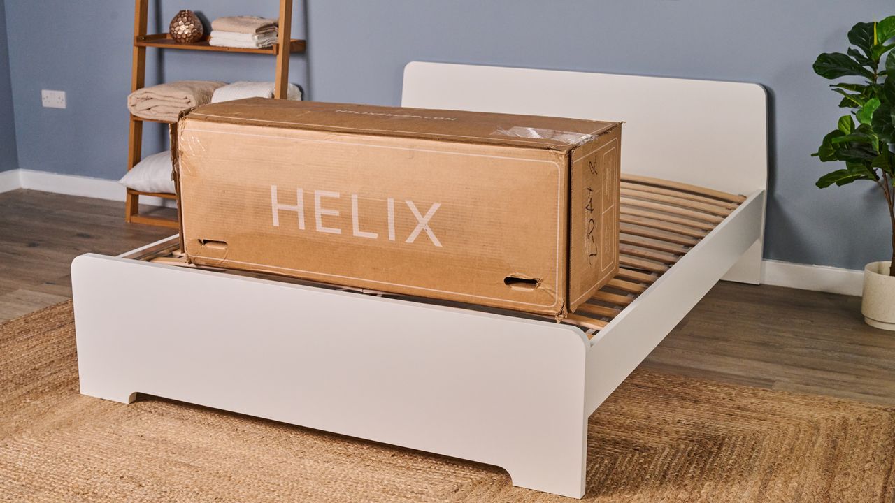 The image shows a Helix box on a white bed frame in a blue bedroom