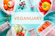 Veganuary background on blue with fresh fruits and vegetables in eco mesh bags, top view