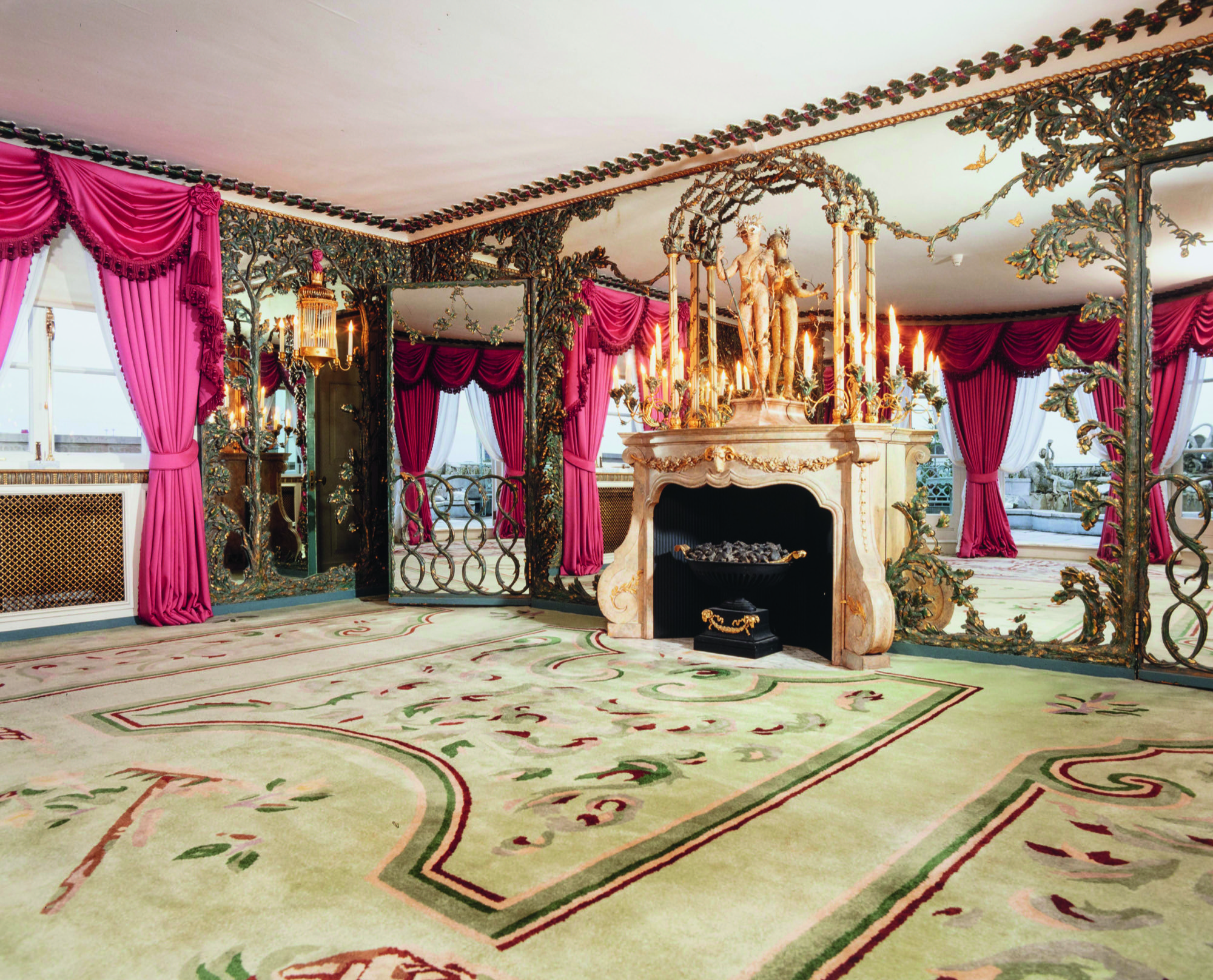 The Messel Suite at the Dorchester. A beige rug, red curtains and brass art deco fittings are reflected in a wall that is all mirror