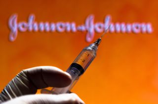 A vaccine syringe in front of a Johnson and Johnson logo.
