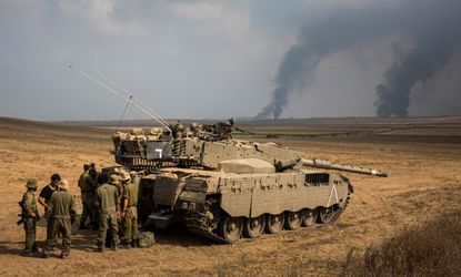 Israeli soldiers stand near a tank as strikes continue in Gaza