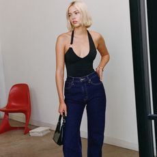 model wears black bodysuit, dark wash jeans, and black handbag