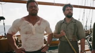 A blood-splattered Alan Ritchson stands next to Henry Cavill on the deck of a boat in The Ministry of Ungentlemanly Warfare.