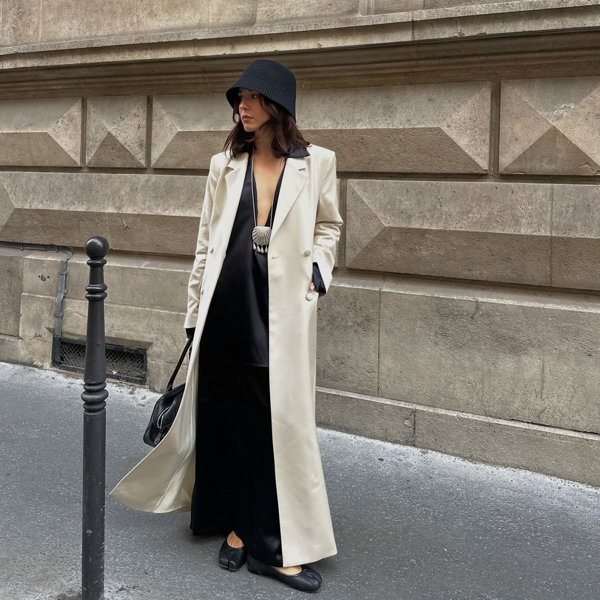 @deborabrosa street style shot in white long coat and black dress and shell necklace underneath
