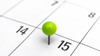 A green pushpin marks the 15th on a calendar.