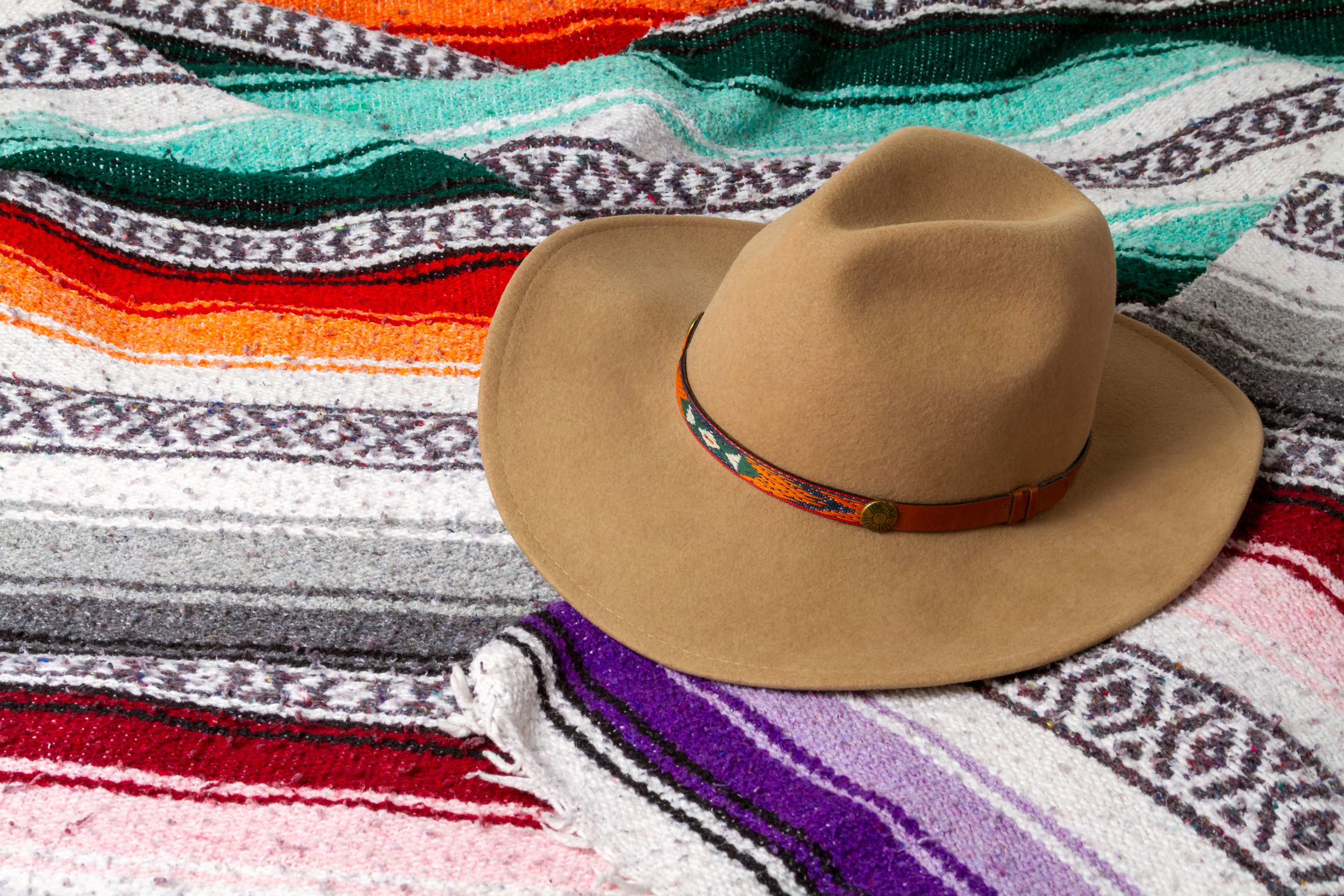 A cowboy hat on a colorful Southwestern blanket