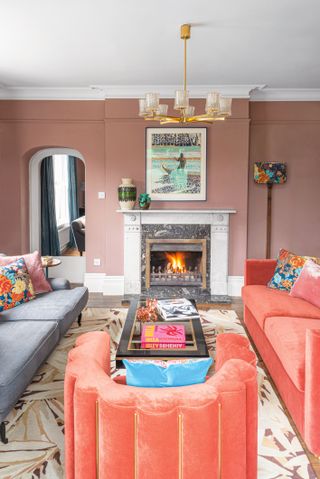 Blush pink living room with orange sofas