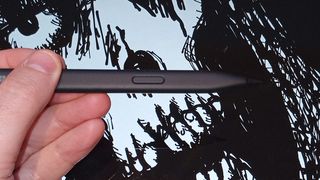 Microsoft Surface Slim Pen 2 review; a hand holds a black stylus in front of a digital drawing of a skeleton's face