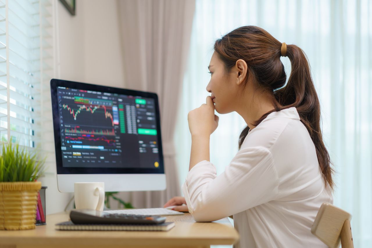 Asian woman at home trading stocks or cryptocurrency