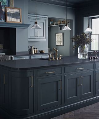 kitchen island color ideas, dark and moody kitchen with dark blue cabinetry and island, trio of pendant lights brass handles, painted ceiling