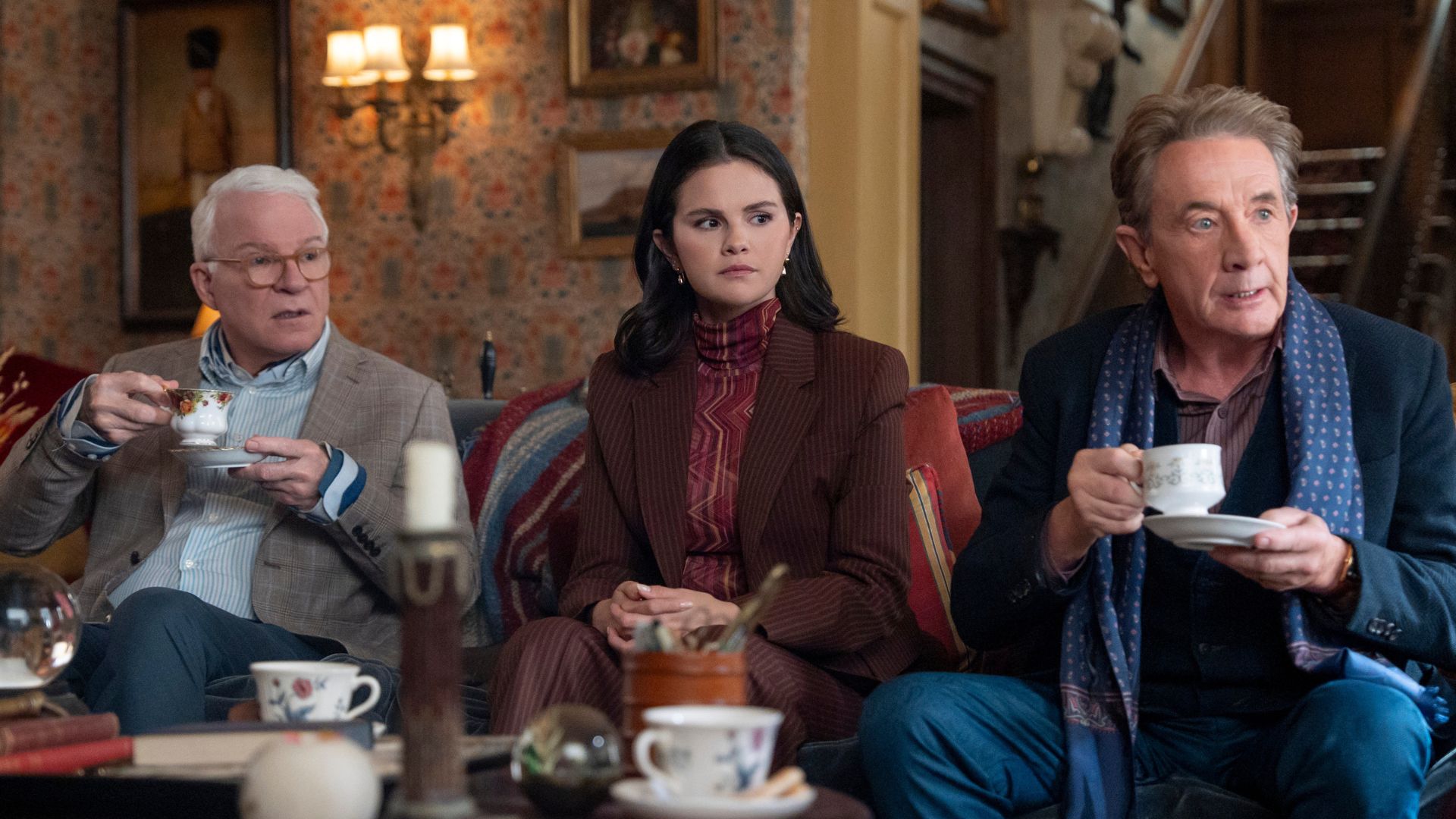 Charles, Mabel and Oliver have tea on a sofa