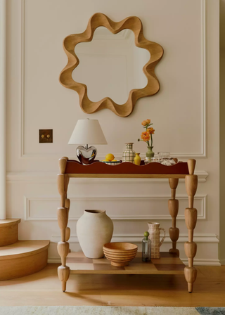 A wooden bar cart with a lamp, a vase and serveware