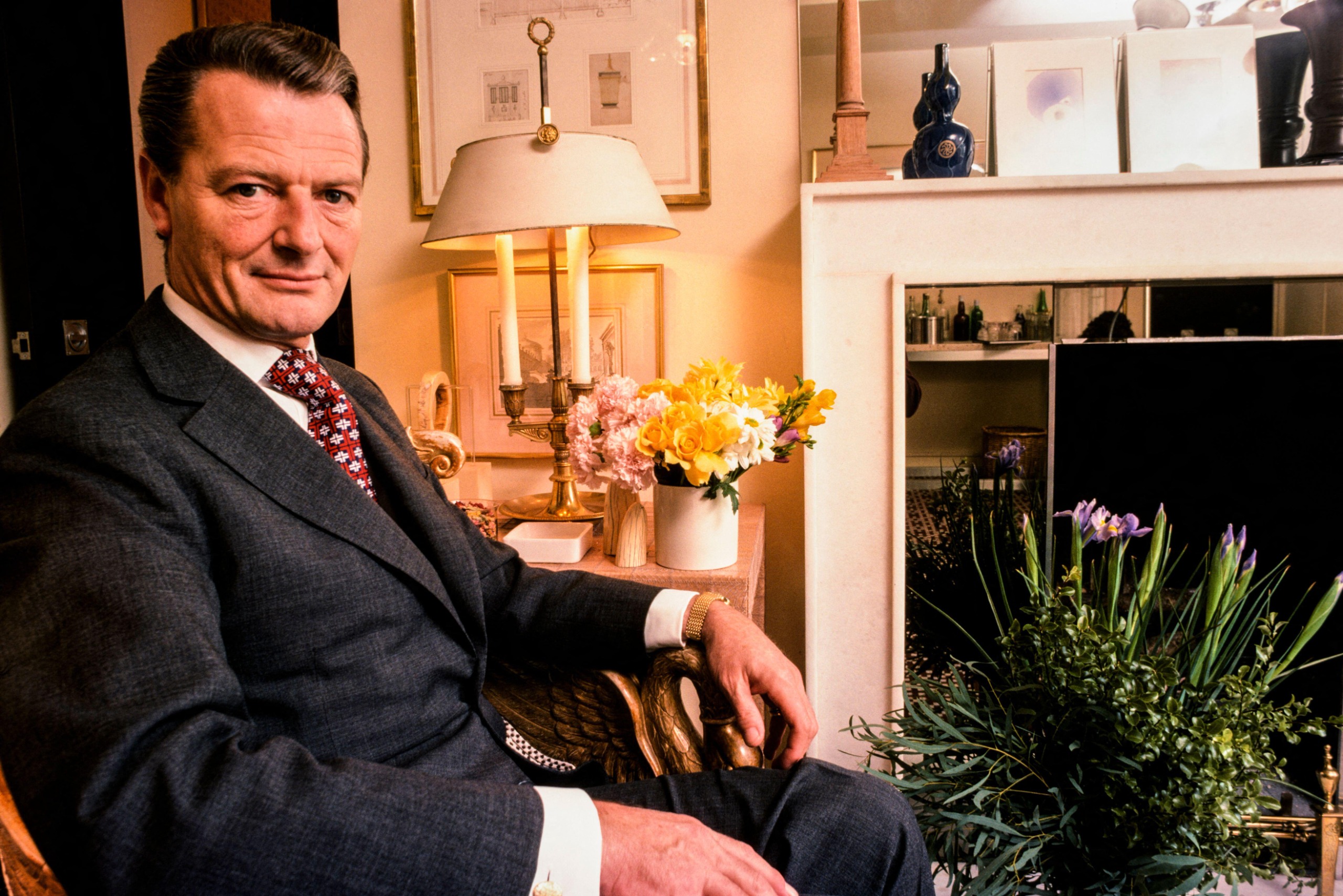 The designer david hicks at his home, sitting in a chair