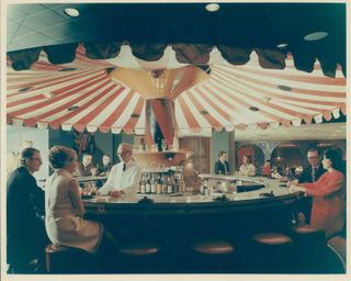 A carousel-shaped bar is captured in a pastel-shaded polaroid picture, featuring multiple people sitting at the counter in vintage clothing.