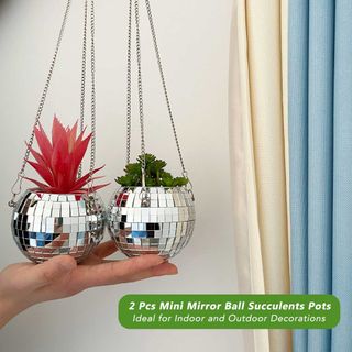 Two disco ball planters with metal chains, both balanced on a hand