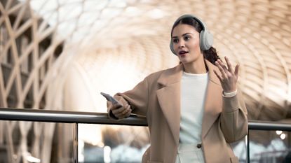 Best wireless headphones 2023, woman wearing wireless headphones and holding phone