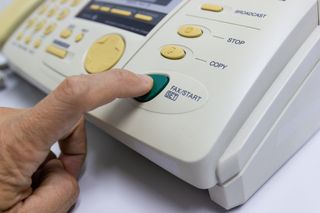 finger pressing button on fax machine