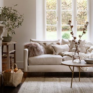 A white living room with rustic textiles and a wooden coffee table