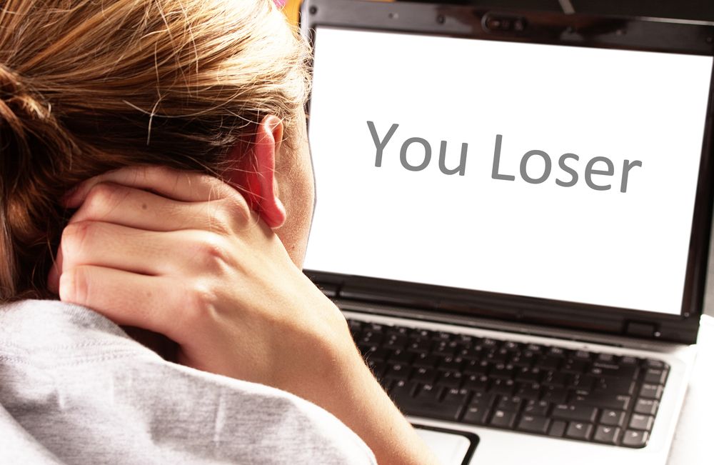 A girl looks at a computer screen that says &quot;You Loser.&quot;