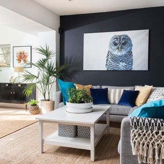 A modern living room with ink blue walls and owl canvas
