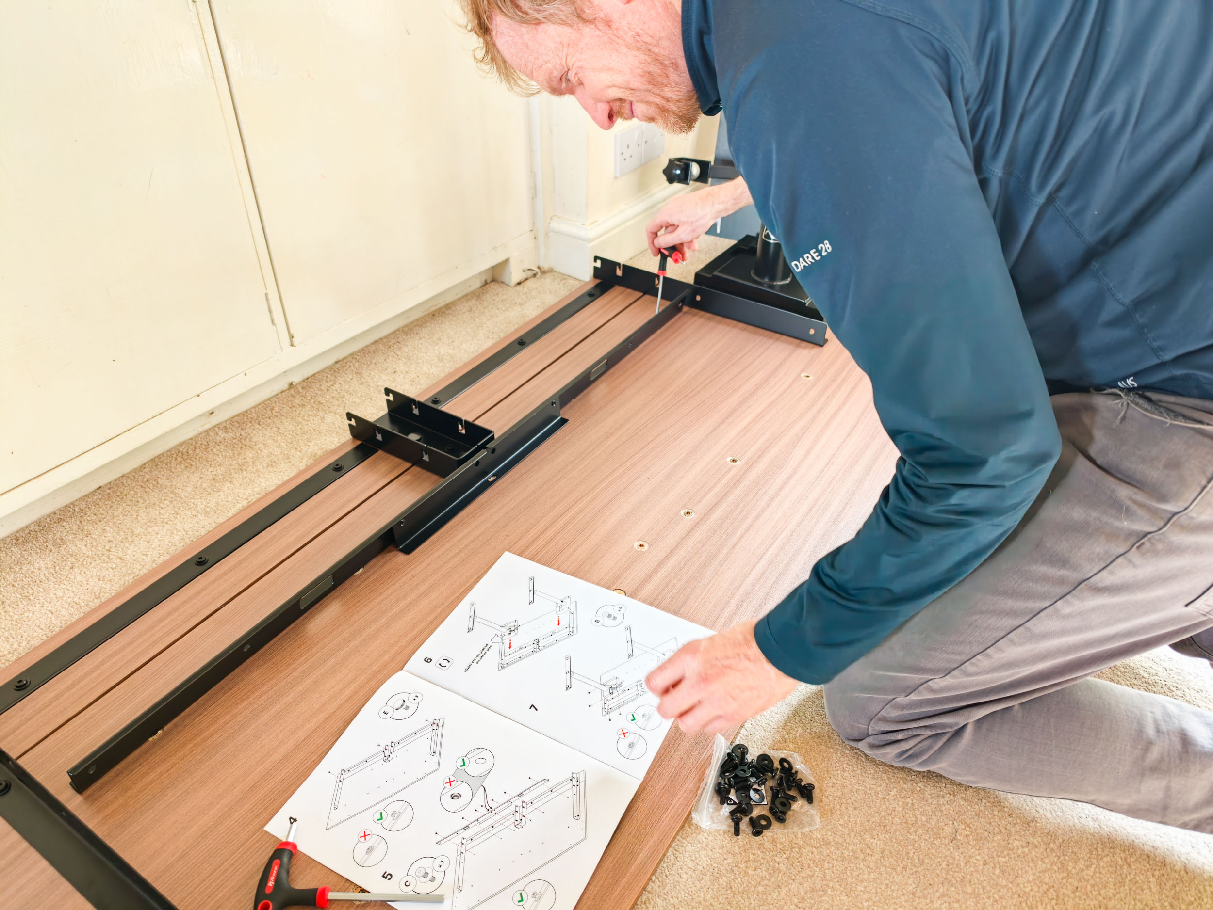 Man assembling the Arozzi Arena Nordico Electric Standing Desk