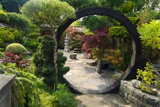 Japanese garden ideas: Japanese garden in England with moon gate, rocks, shrubs and trees