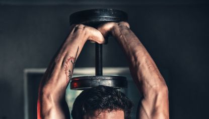 best dumbbells: Pictured here, a muscular man lifting a dumbbell over his head