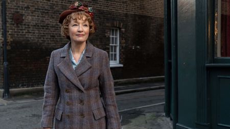 Mrs. Harris (Lesley Manville) stands in a London street in a still from "Mrs. Harris Goes To Paris"