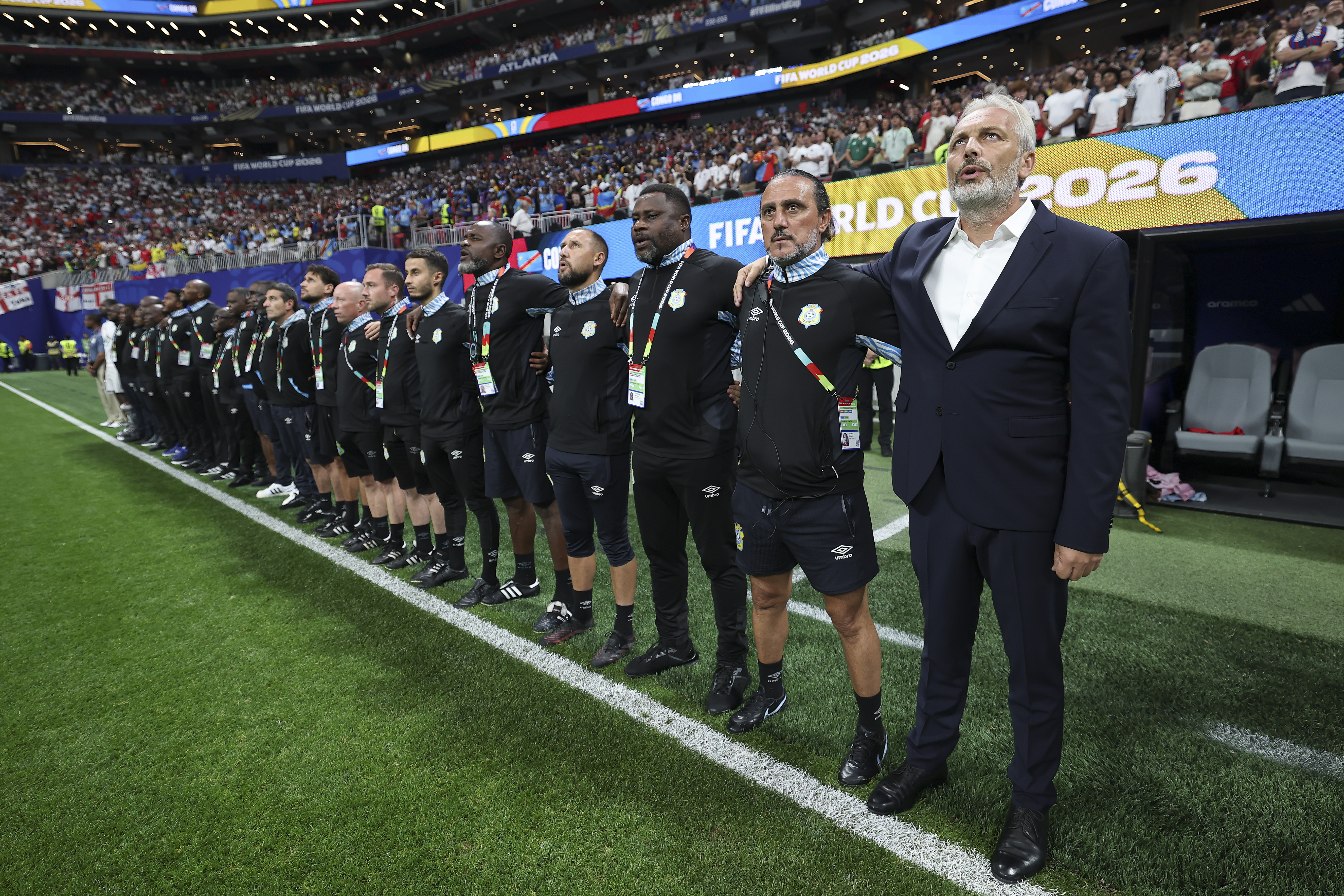 ATLANTA, GEORGIA - JULY 01: Sebastien Desabre, Head Coach of Congo DR, and team staffs line up for the national anthem before the FIFA World Cup 2026 Round Of 32 match between England and Congo DR at Atlanta Stadium on July 01, 2026 in Atlanta, Georgia. (Photo by Steph Chambers - FIFA/FIFA via Getty Images)