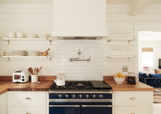 An all-white kitchen with butcher block countertop