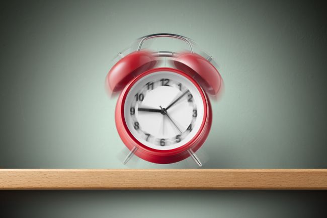 A red alarm clock ringing on a shelf